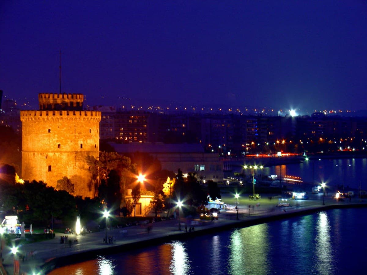 The White Tower of Thessaloniki lit up at night above the waterfront